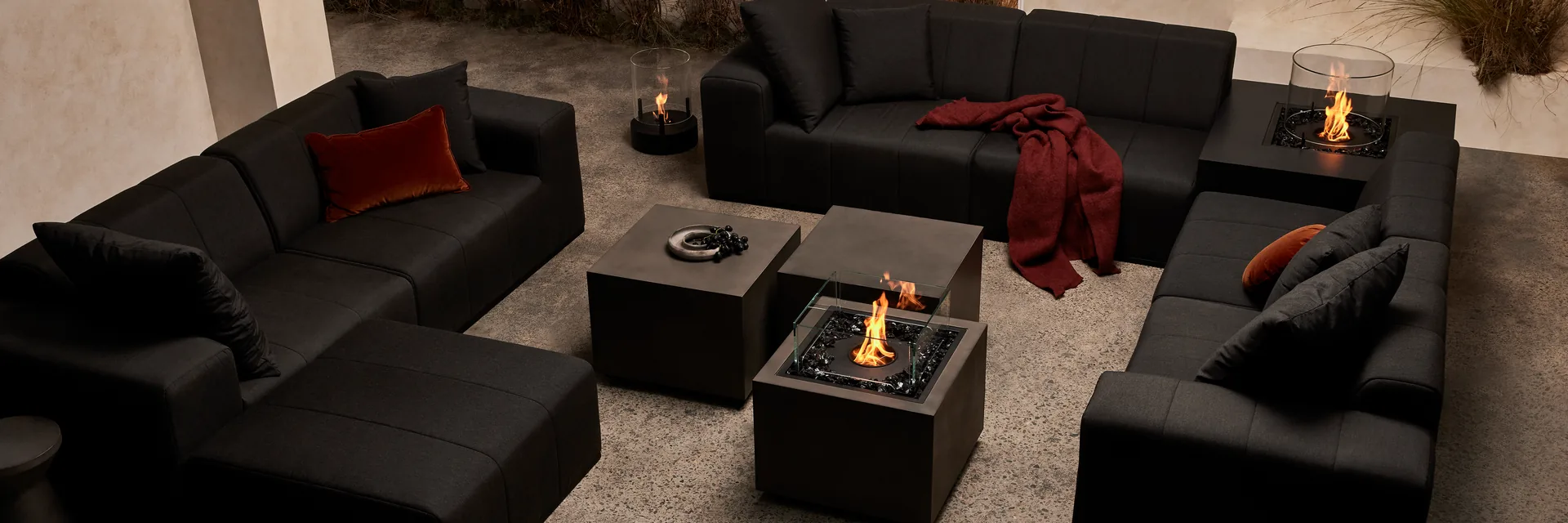 EcoSmart Sidecar 24 fire table burning between black modular sofas, with a Chaser 38 fire table beside the sofa behind