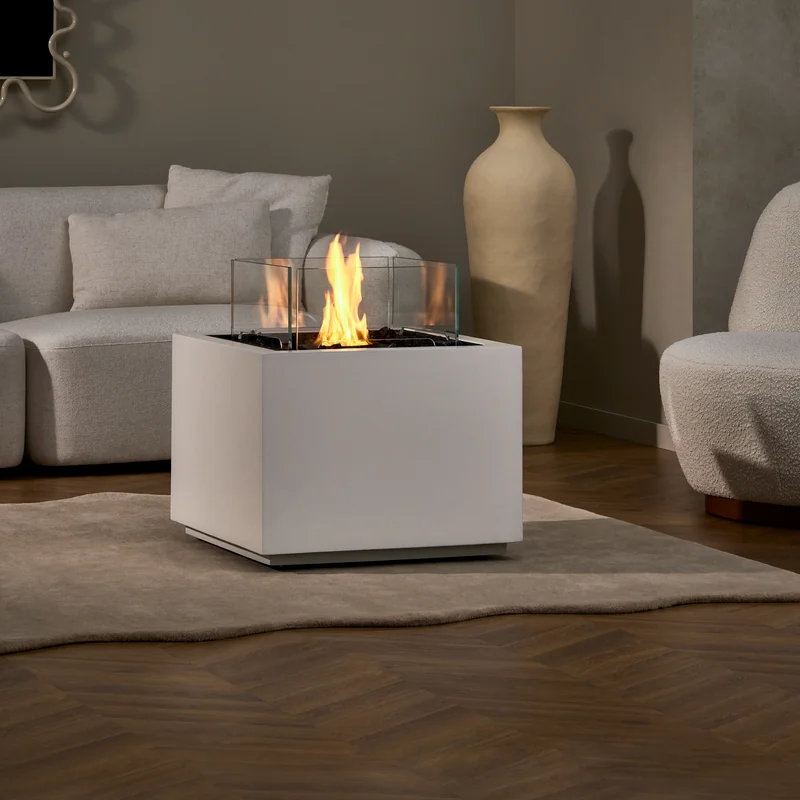 EcoSmart Sidecar 24 fire table in white with a glass screen, burning beside a white sofa and tall ceramic vases