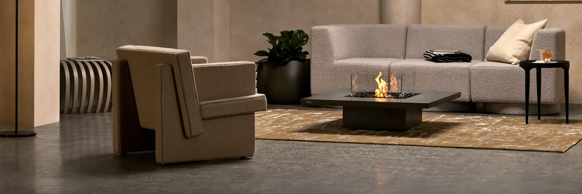 Low square EcoSmart Vertigo 40 fire table burning on a rug between a sculptural armchair and a pale sofa