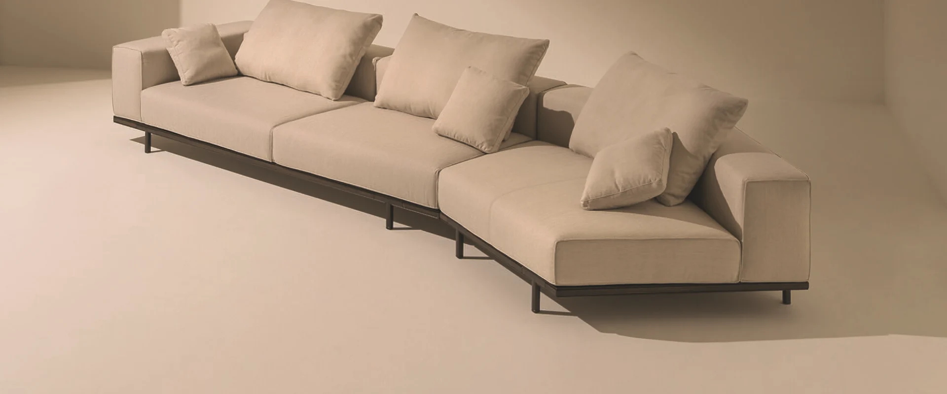 Ethimo Costiera modular outdoor sofa with beige cushions in a sunlit set with pale walls