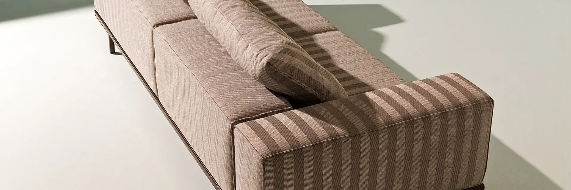 Ethimo Costiera sofa upholstered in striped fabric, seen from above beside pale green water