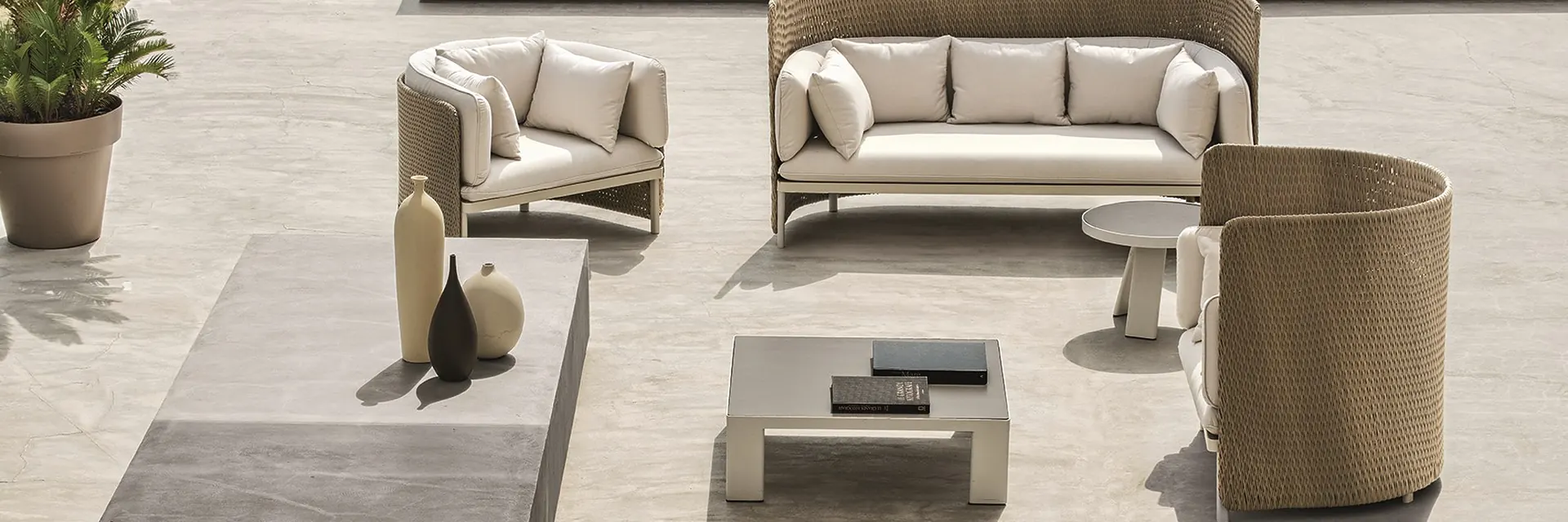 Ethimo Esedra sofa and armchairs with woven backs around a low table on a stone terrace above the sea