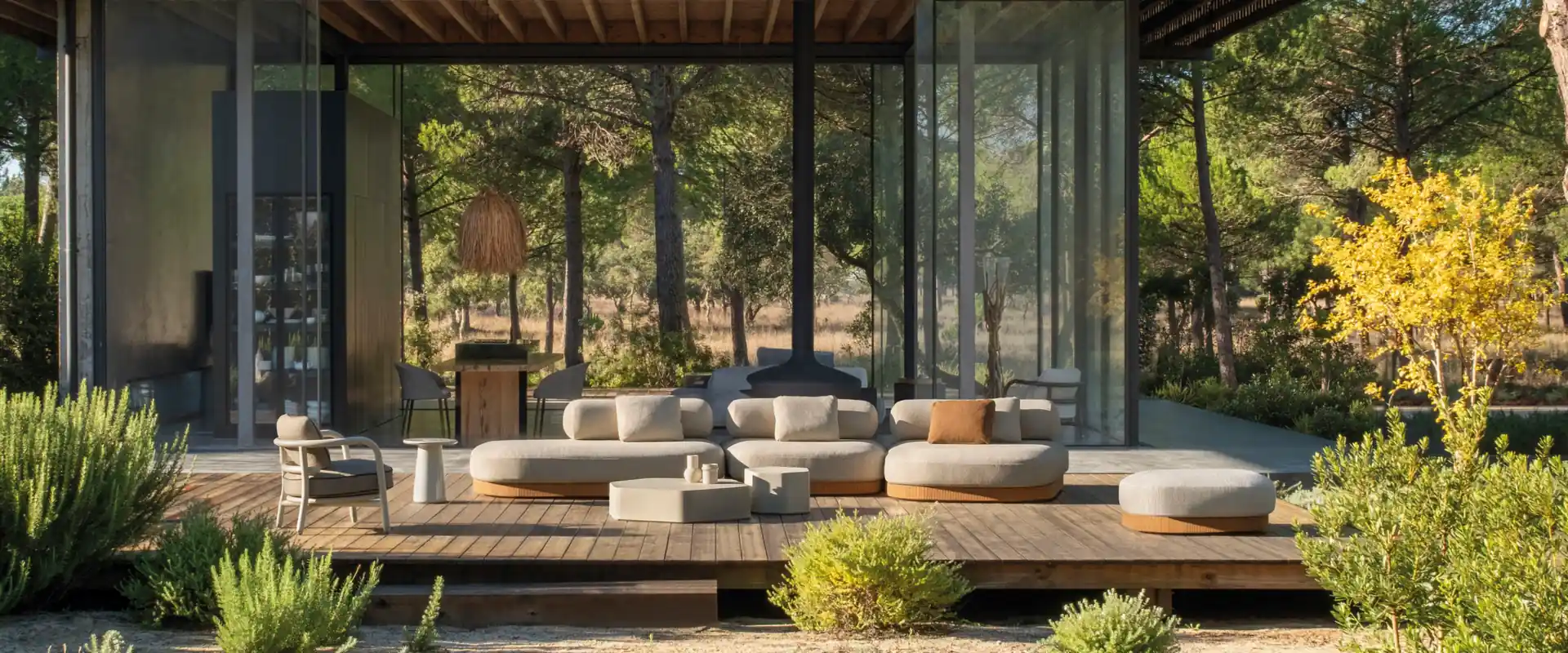 Expormim Brae modular sofas and ottomans on the deck of a glass pavilion surrounded by pine trees and shrubs