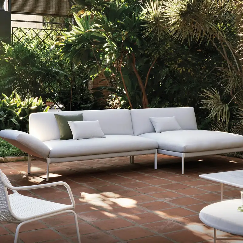 Expormim Livit outdoor sofa with a chaise module on a terracotta-tiled patio, surrounded by lush plants