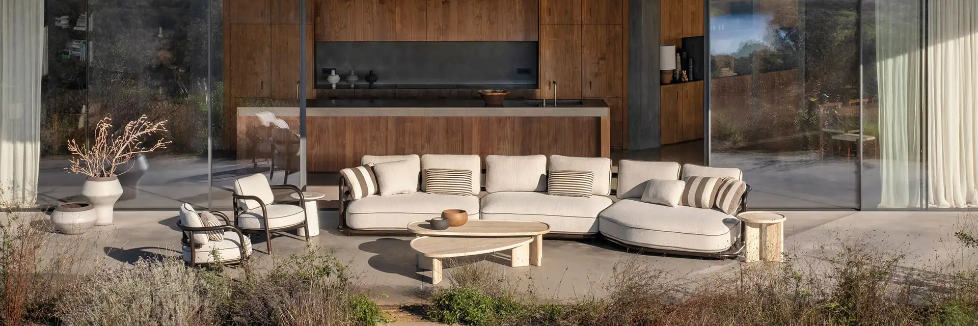Expormim Meridies curved sofa and armchairs with striped cushions on the terrace of a house with timber walls