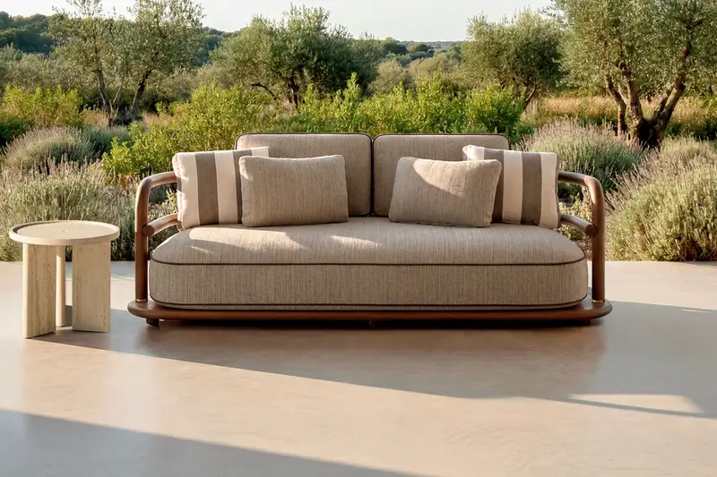 Expormim Meridies outdoor sofa with striped cushions and a side table on a terrace overlooking olive trees and scrubland
