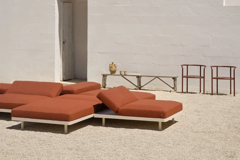 Fast Unduetre modular loungers with terracotta cushions on gravel in front of a white building with an outside staircase