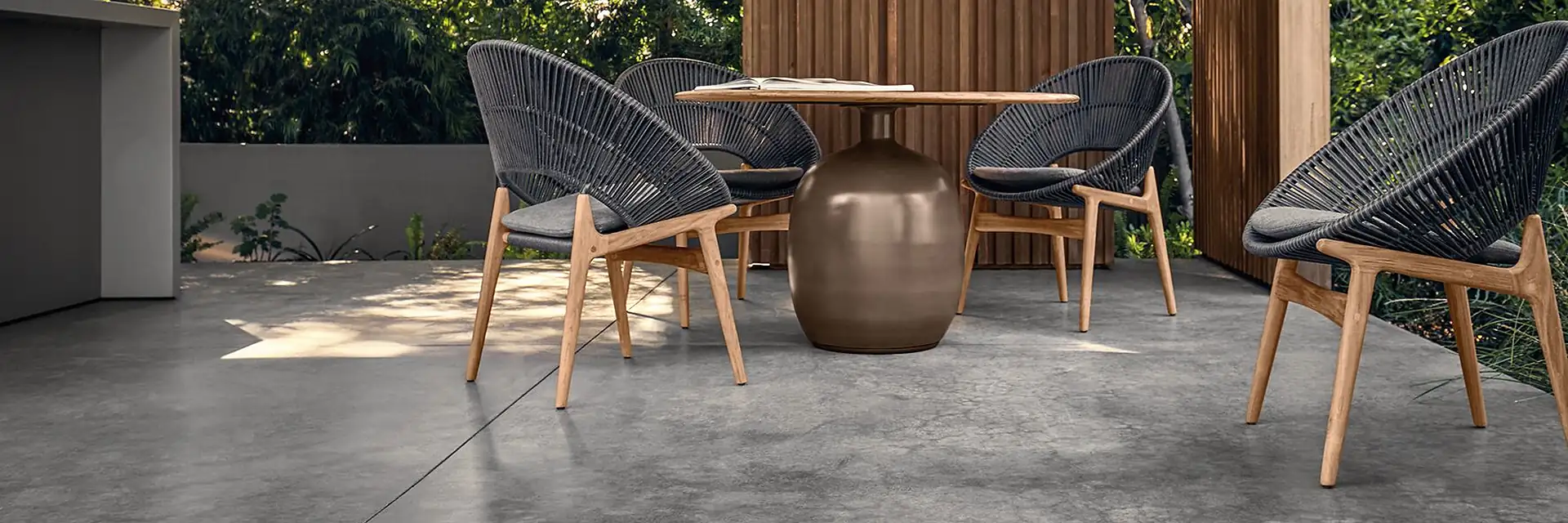 Gloster Bora rope dining chairs around a round table under a timber pergola with a woven pendant lamp