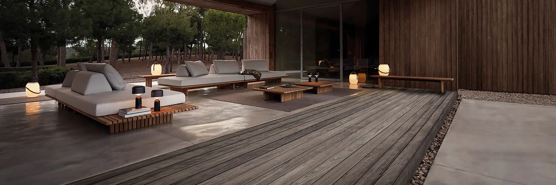Gloster Deck modular platform seating on a dark timber deck under a pitched timber roof at dusk