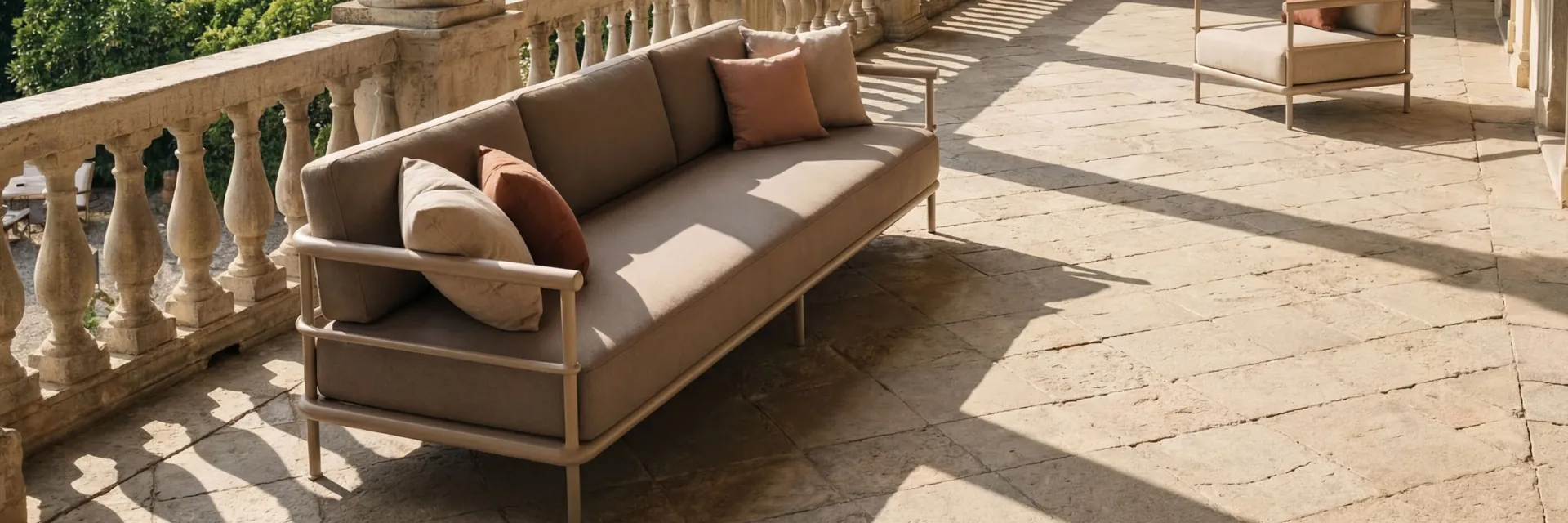 Kettal Alize sofa with brown cushions in the sunlit loggia of a villa, with stone columns and terraced gardens beyond