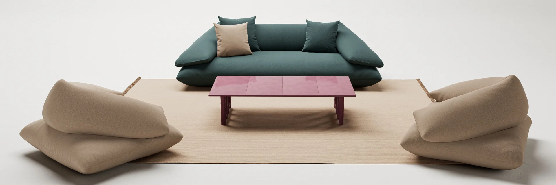 Kettal Grosso sofa in teal and two soft armchairs in beige around a red-topped coffee table on a rug, against a pale studio backdrop