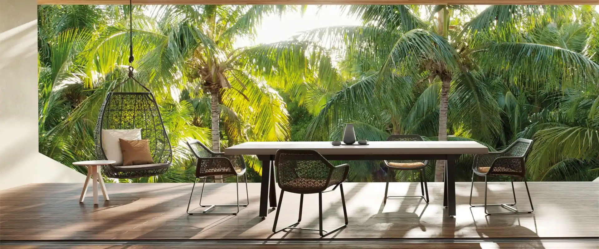 Kettal Maia dining chairs and a hanging egg chair on a covered terrace with a wooden ceiling, opening onto a palm garden