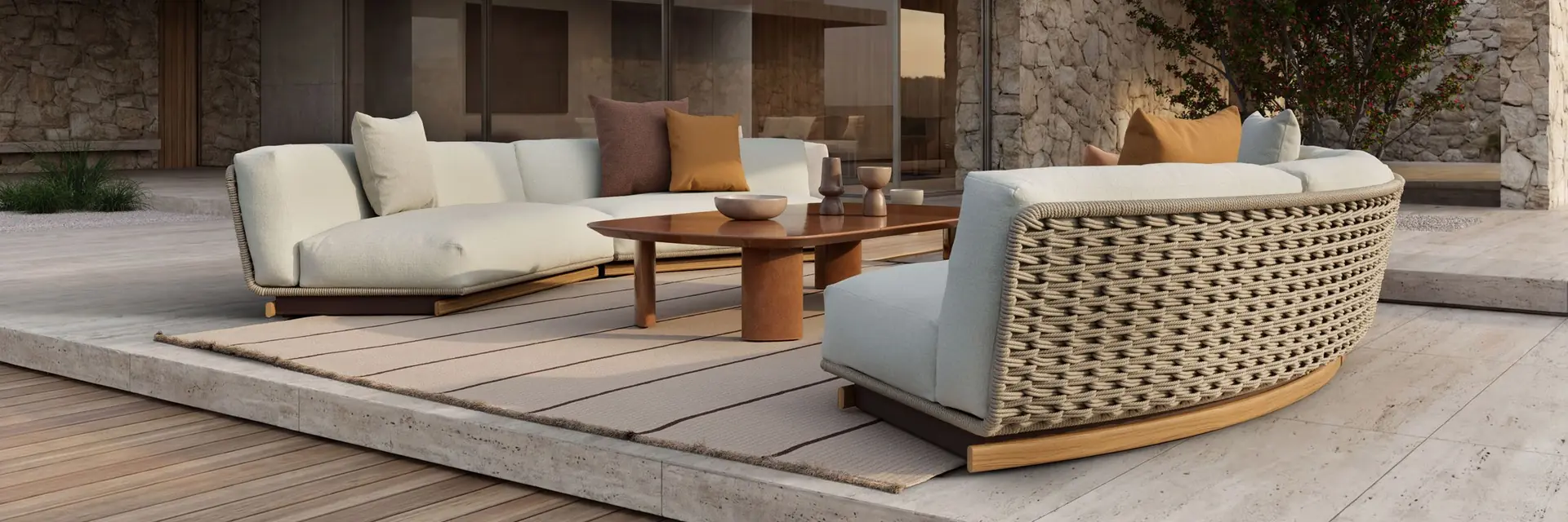 Kettal Tilos curved sofas with woven backs and low tables on the terrace of a stone house under a concrete canopy