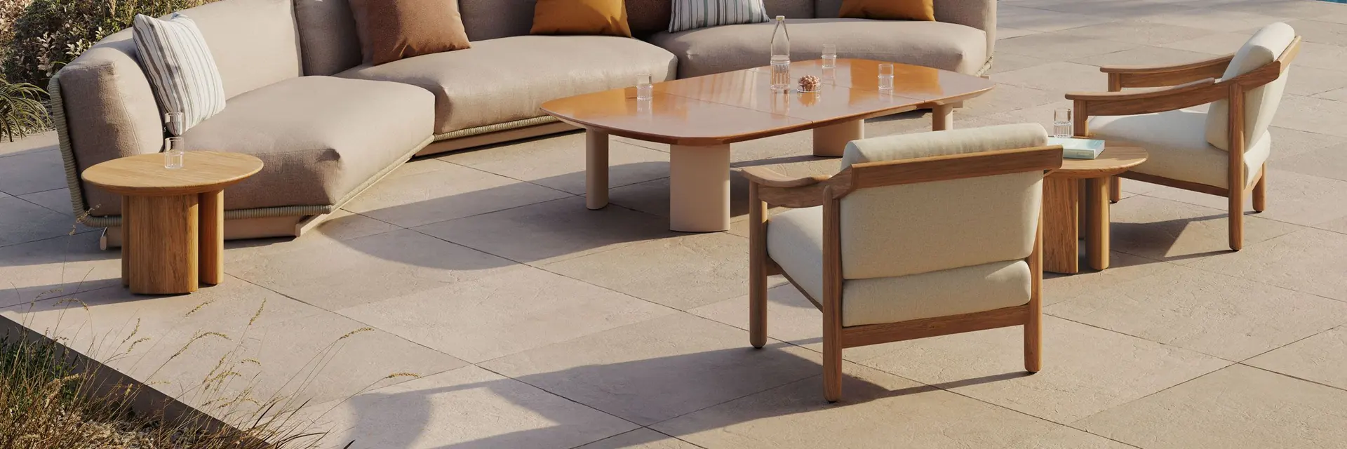 Kettal Tilos curved sofa, low tables and teak armchairs on a stone terrace by the sea