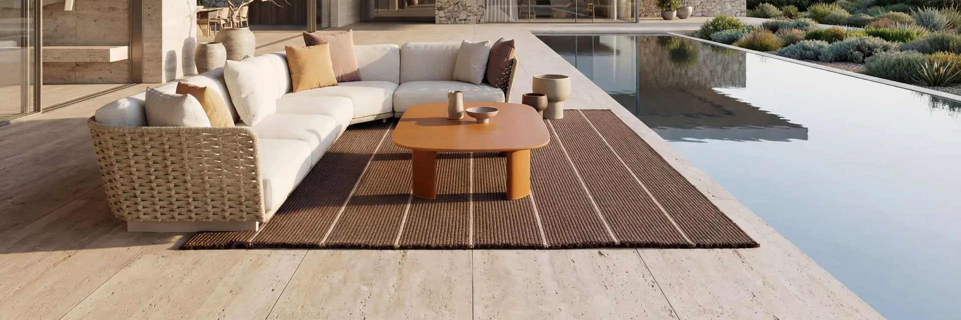 Kettal Tilos curved sofa and low table under a timber porch, beside an infinity pool that looks out to the sea