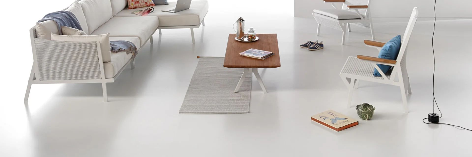 Kettal Vieques modular sofa, armchairs and a teak low table arranged in a white studio set