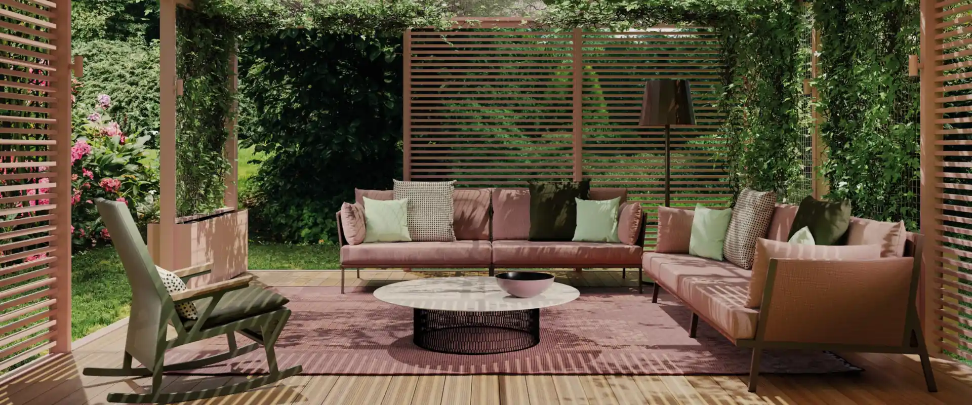 Kettal Vieques sofas with pink cushions and a rocking armchair under a slatted pergola covered with climbing plants