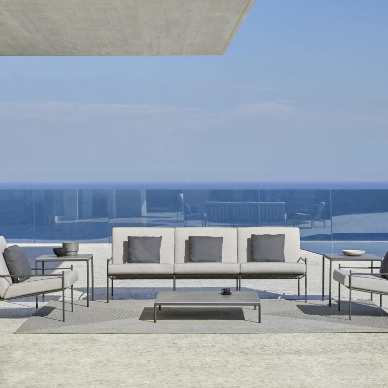 Point Min outdoor sofa and two armchairs with a low table on a pale terrace overlooking the sea