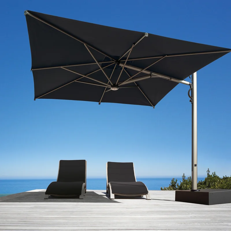 Black Scolaro Galaxia Astro cantilever parasol over two dark sun loungers on a deck beside an infinity pool, with the sea behind under a deep blue sky