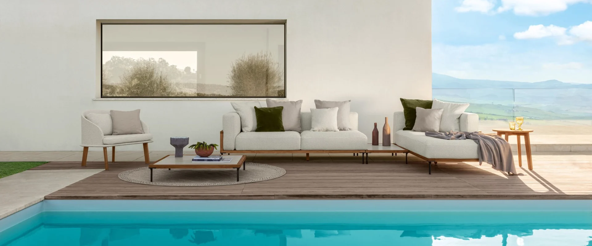 Talenti Cleo modular sofa and coffee table on a terrace beside a turquoise pool, in front of a white villa