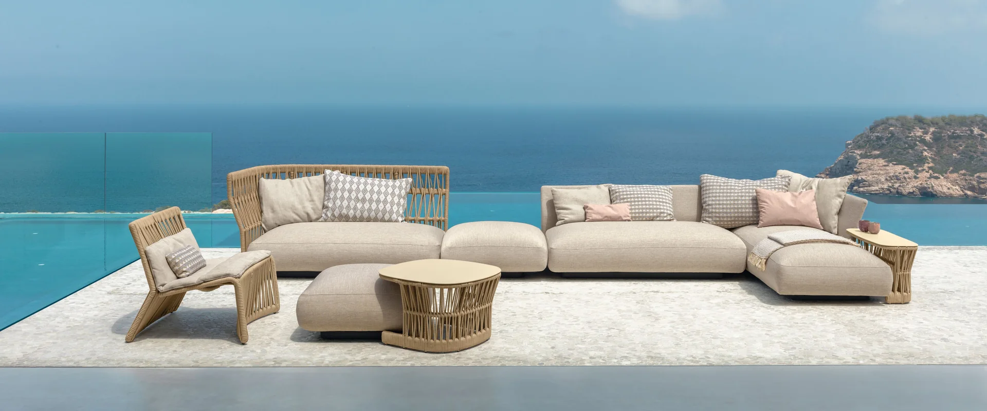 Talenti Cliff sofa, lounge chair and round coffee tables on a terrace above a turquoise sea under a blue sky