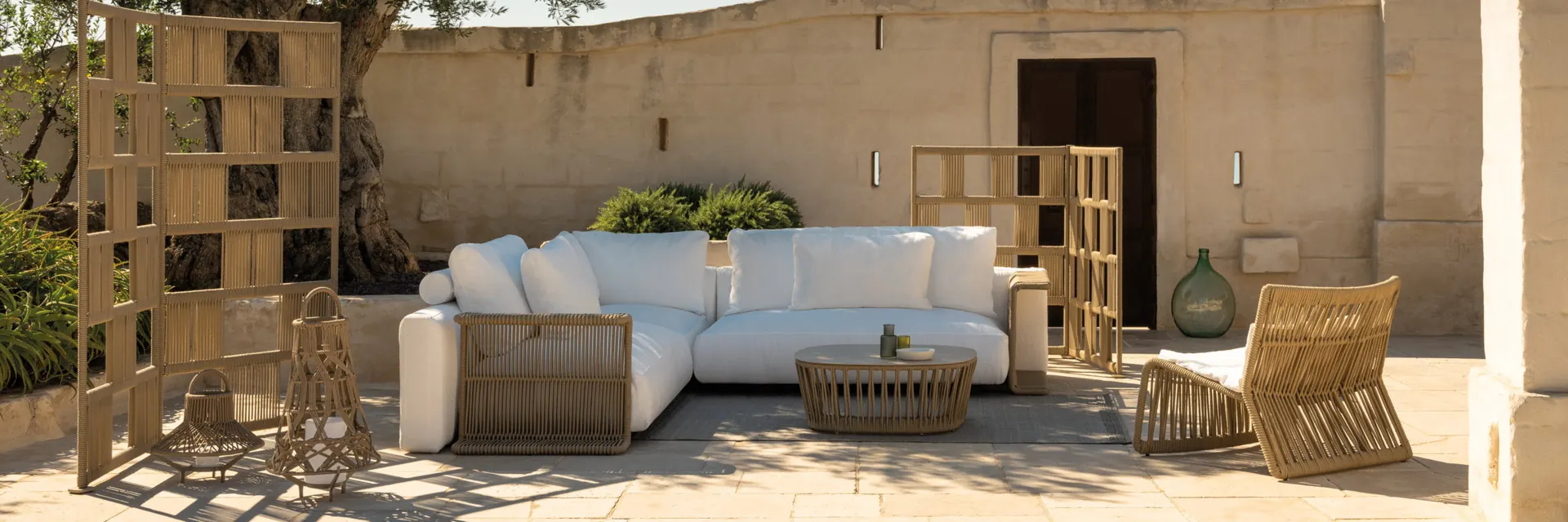 Talenti Cliff sofa and armchair with woven frames in a sunlit stone courtyard with timber lattice screens