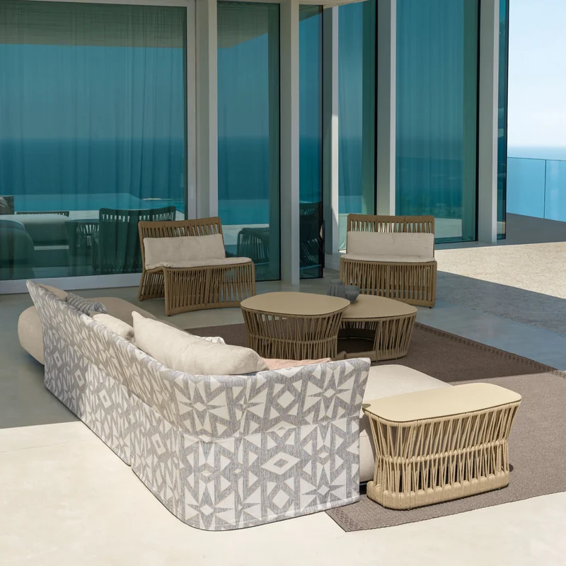 Talenti Cliff sofa and armchairs with woven rope sides around a round table on the terrace of a glass-walled villa