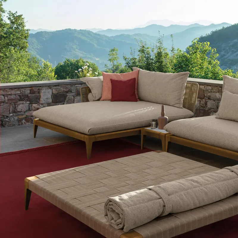 Talenti Cruise teak daybeds with beige mattresses and red cushions on a terrace overlooking wooded hills