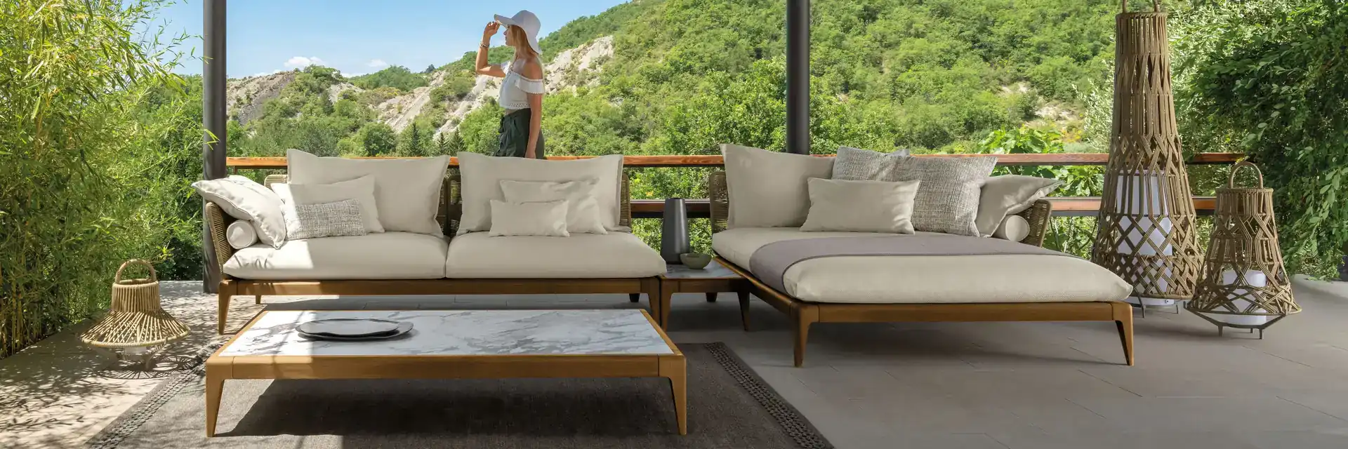 Talenti Cruise Teak sofa and coffee table under a timber pergola, with a woman looking out over wooded hills