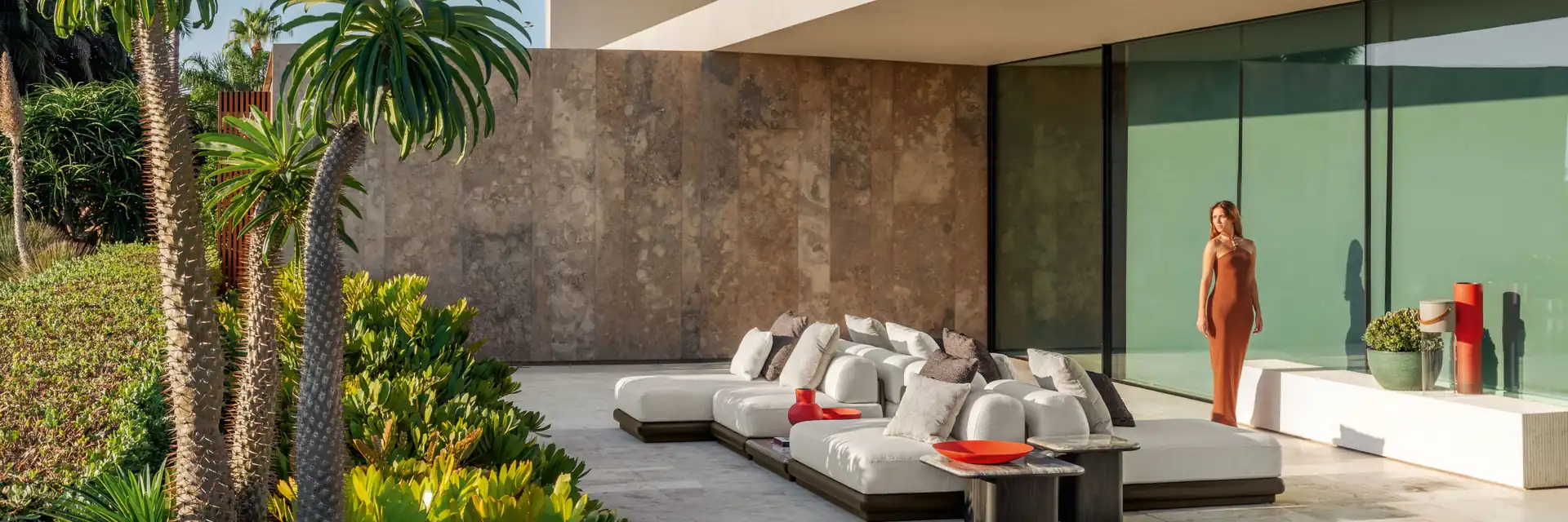 Talenti Itaca modular seating with coloured cushions on the terrace of a modern villa, beside palm trees