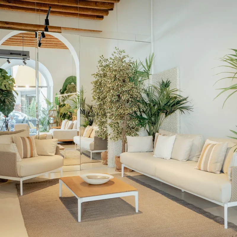 Talenti Leaf sofas with cream cushions around a low table in a bright veranda with arches and potted palms