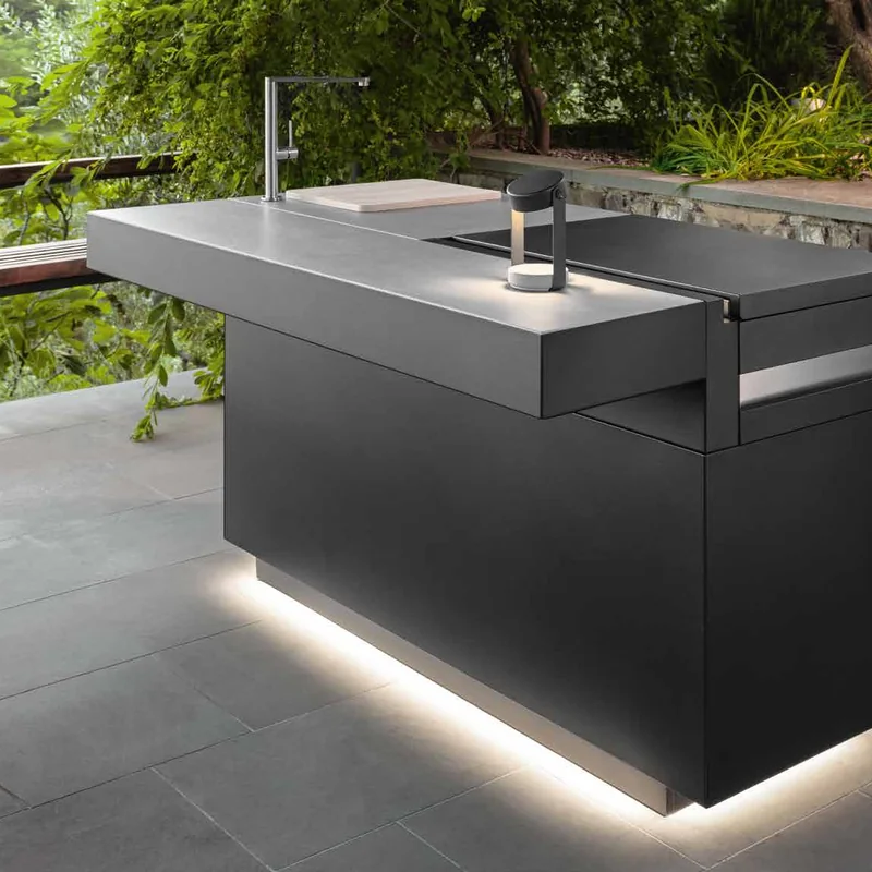 Dark Talenti outdoor kitchen island with a tap and a lit plinth on a terrace beside a dry-stone wall