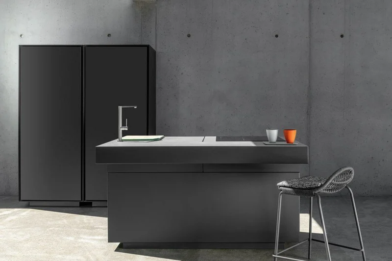 Dark Talenti Tikal outdoor kitchen island with a bar stool and a tall cabinet in a concrete courtyard