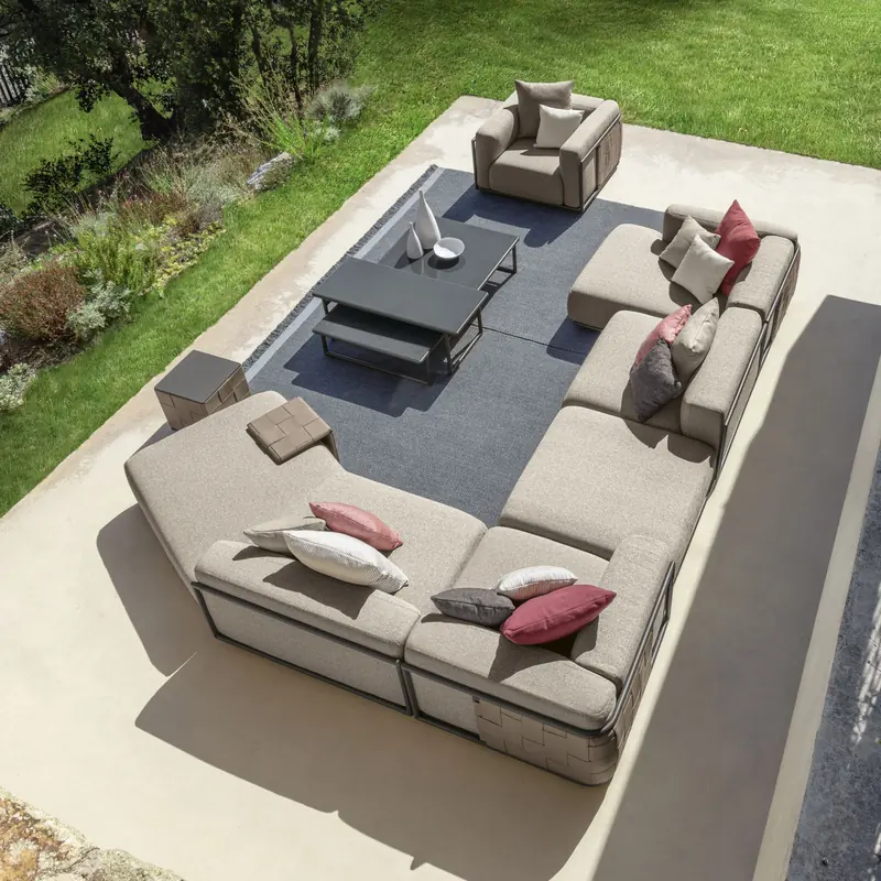Talenti Tresse corner sofa with gray cushions and an armchair on a terrace beside a lawn, seen from above