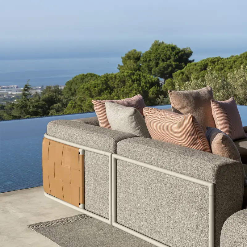 Talenti Tresse sofa seen from behind, with teak panels and beige cushions, on a terrace above a wooded coast