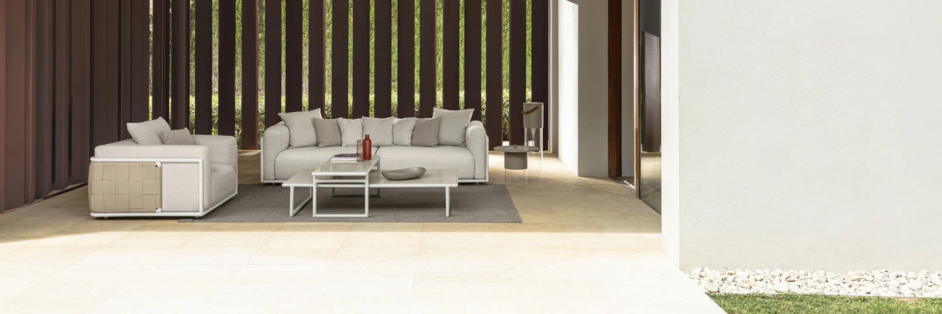 Talenti Tresse sofa and armchairs under a white canopy with a slatted timber wall, opening onto a lawn