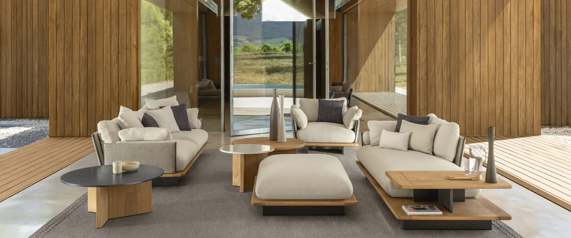 Talenti Venice sofas and coffee tables under the pitched roof of a timber pavilion open to a garden