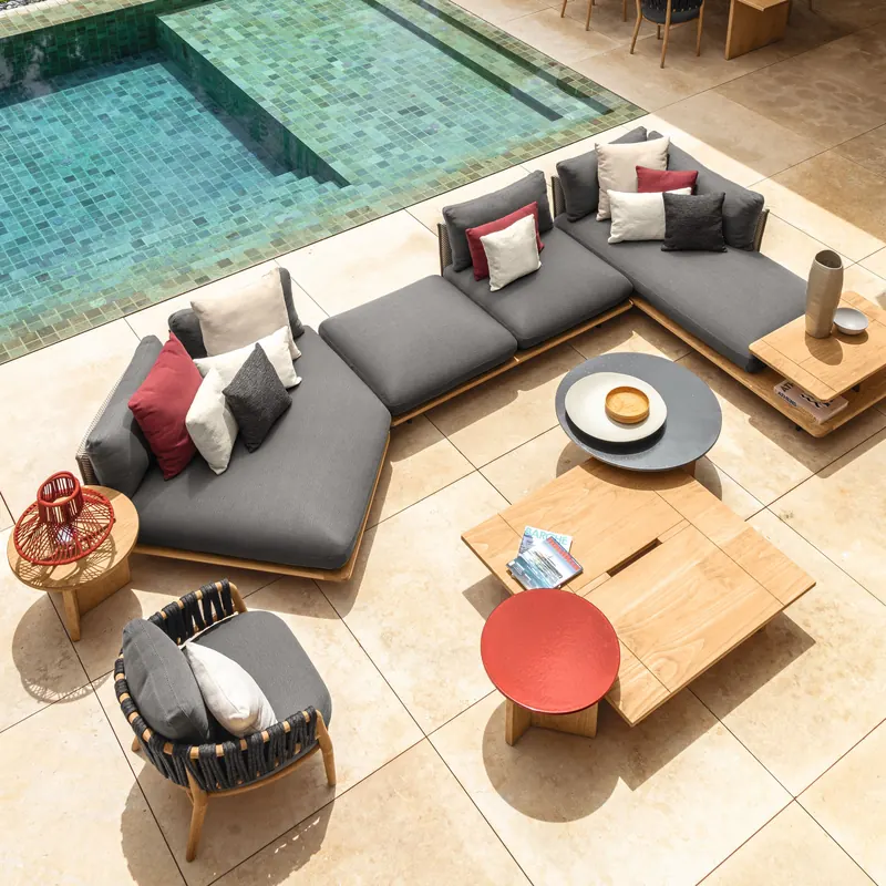 Talenti Venice corner sofa with dark cushions and round colored tables on a stone terrace beside a mosaic pool, seen from above
