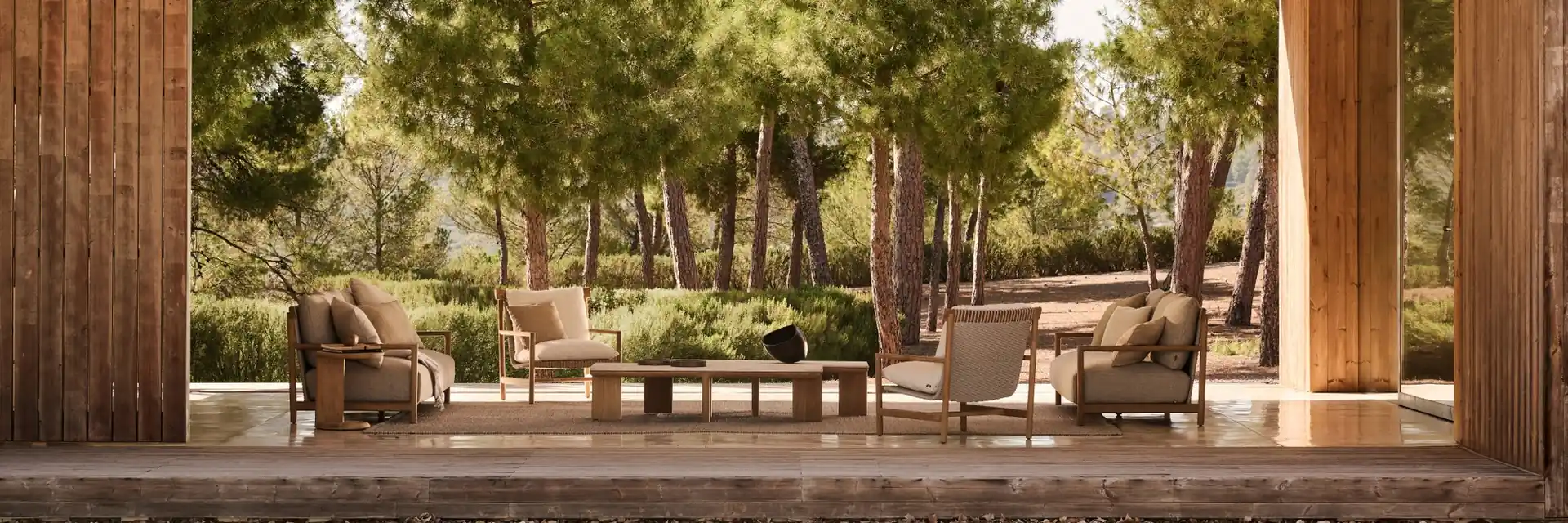 Tribù Amanu sofas and low table in a pine garden, framed by a timber portico