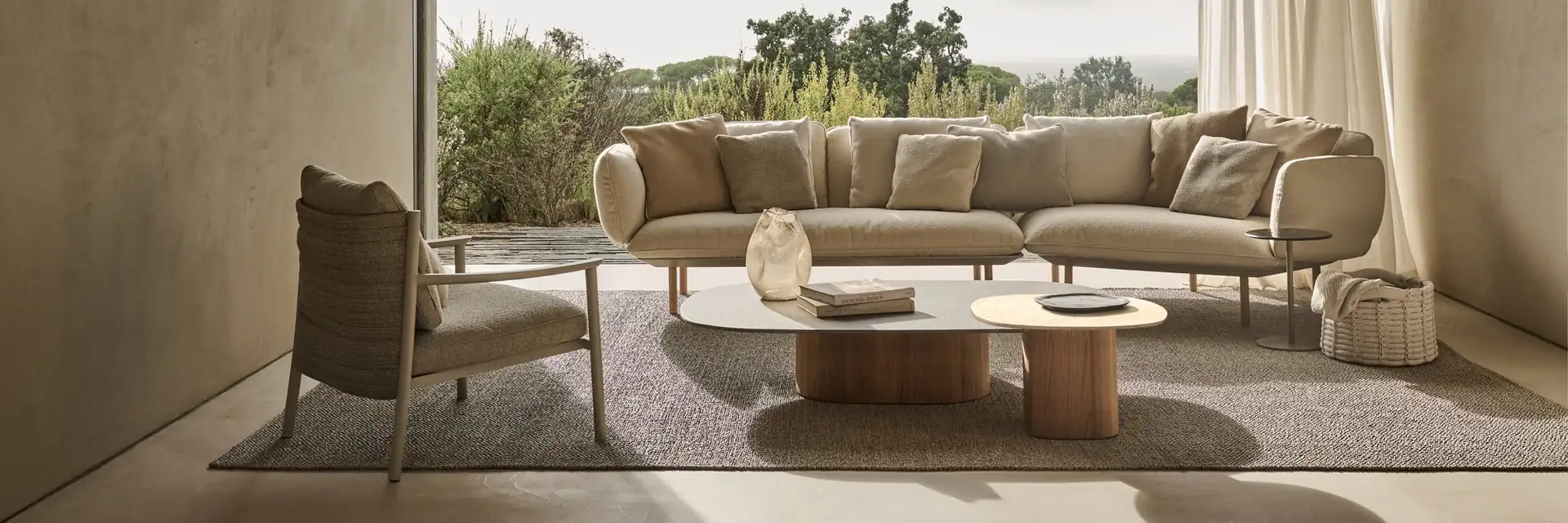 Tribù Mare curved sofa and coffee table under a pitched roof opening onto a garden