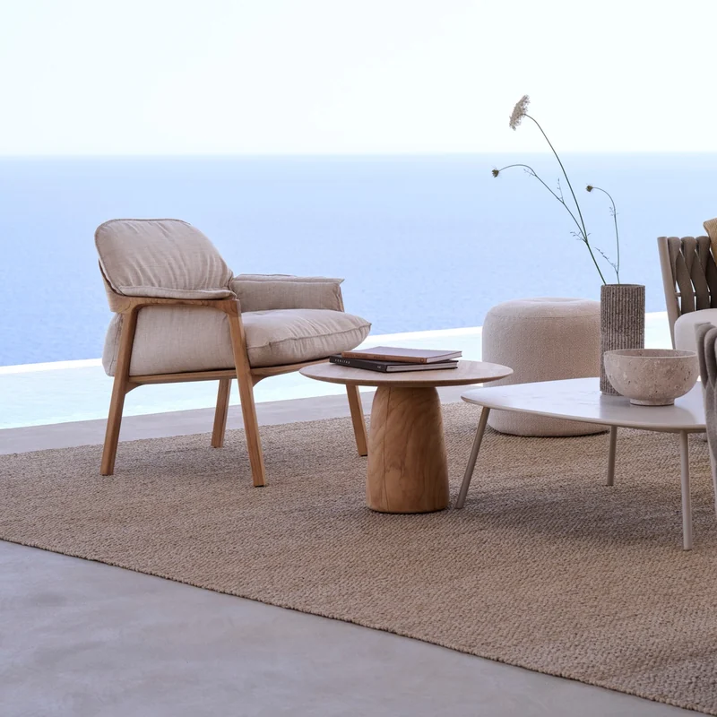 Tribù Nomad lounge chair with round side tables on a terrace overlooking the sea