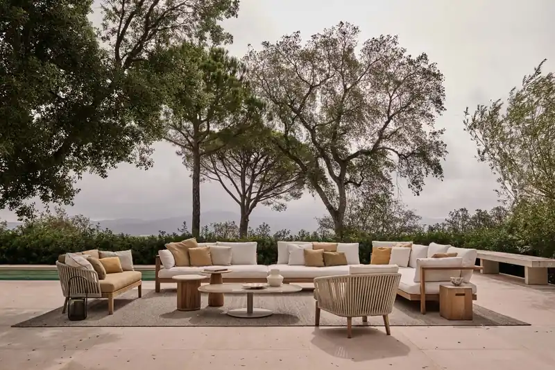 Tribù Pure sofas and armchairs around low tables on a garden terrace beside a pool, under mature trees