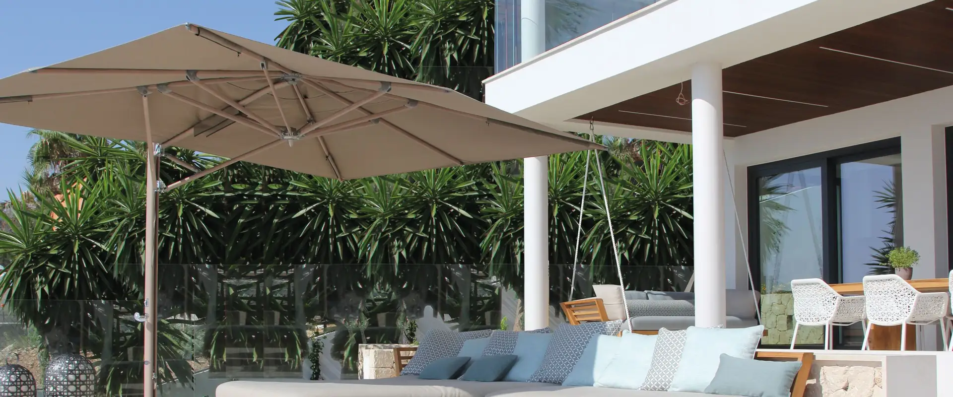 Taupe Tuuci Ocean Master MAX cantilever parasol shading a lounge sofa on a white villa terrace in Spain