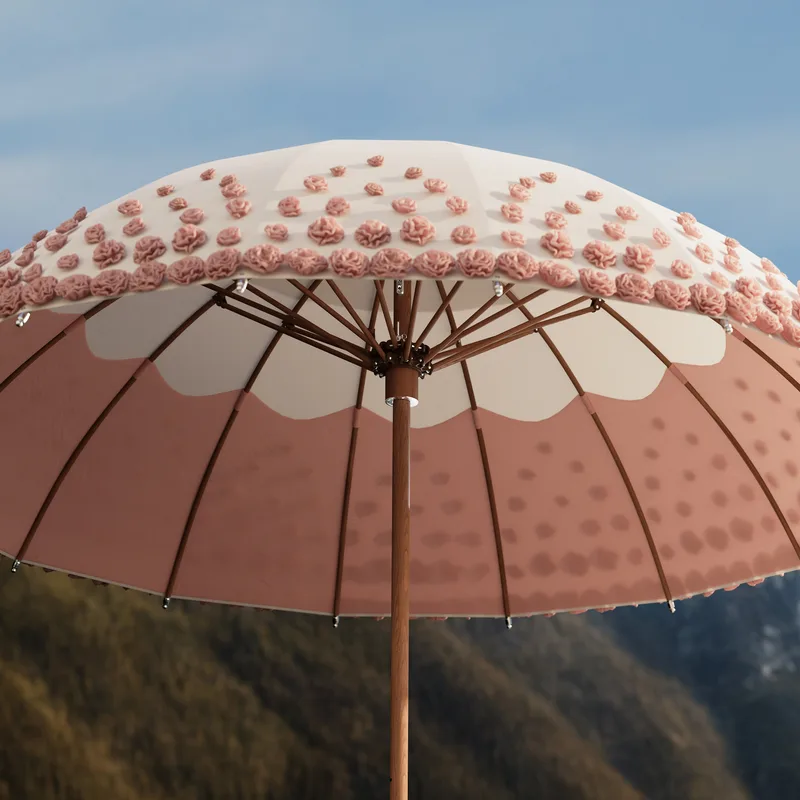Close-up of a Tuuci Ocean Master MAX Bolero Ombré Blossom canopy, pink blossoms on white fabric against mountains and blue sky