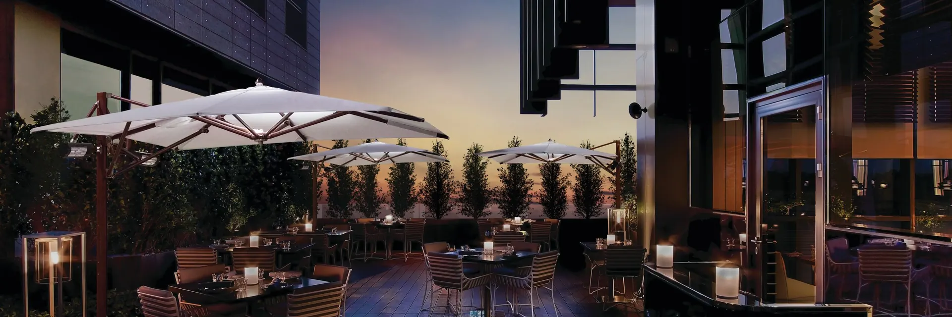 Tuuci Ocean Master MAX Classic parasols with integrated lights and heaters over a bar terrace at dusk