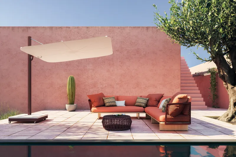 Umbrosa Versa UX cantilever parasol over an outdoor sofa against a terracotta wall with an olive tree