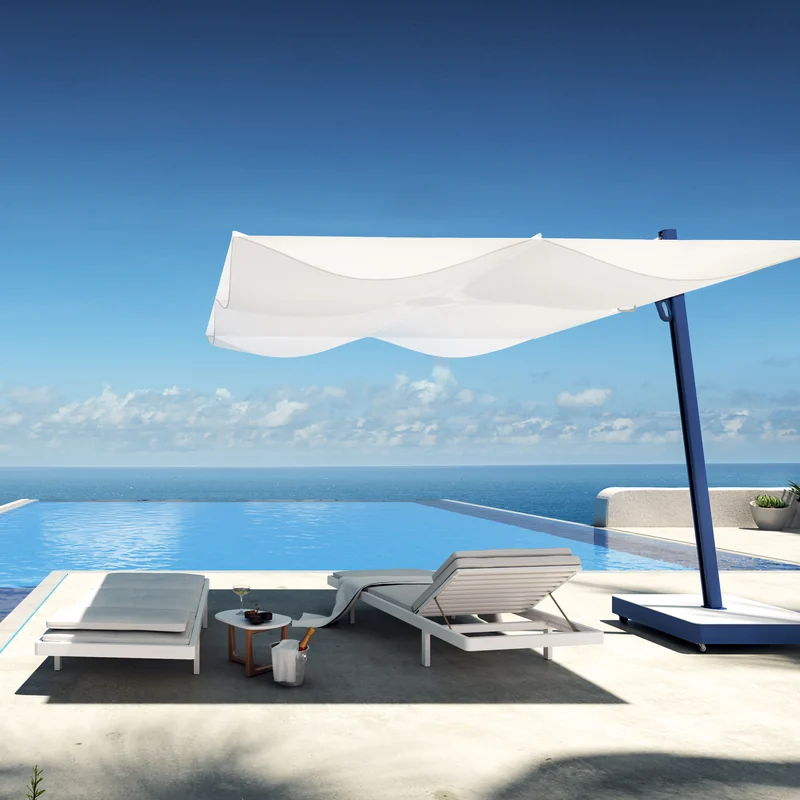 White Umbrosa Versa UX cantilever parasol on a navy blue mast shading two sun loungers beside an infinity pool overlooking the sea