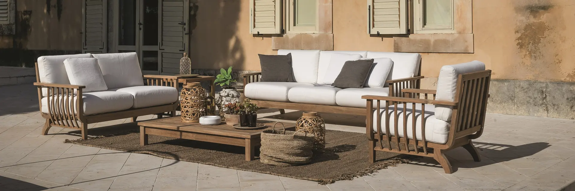 Unopiù Chelsea teak sofas and armchairs with white cushions in the courtyard of an ochre villa