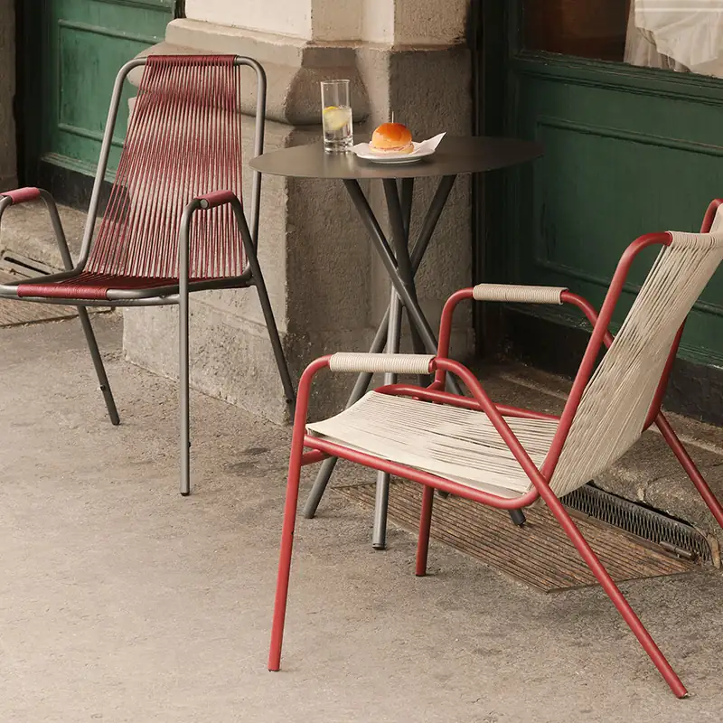 Unopiù Coco armchairs with woven cord seats and a small round table on a pavement, outside a green wooden doorway