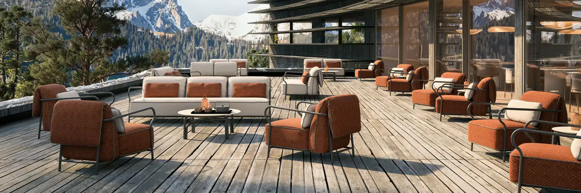 Unopiù Salo armchairs and sofas in terracotta fabric on the timber terrace of a modern building, with snow-capped mountains behind